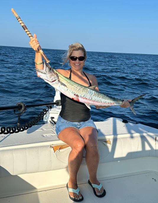 A woman is sitting on a boat holding a large fish